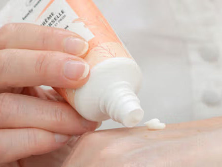 Une femme qui s'applique la crème universelle sur ses mains