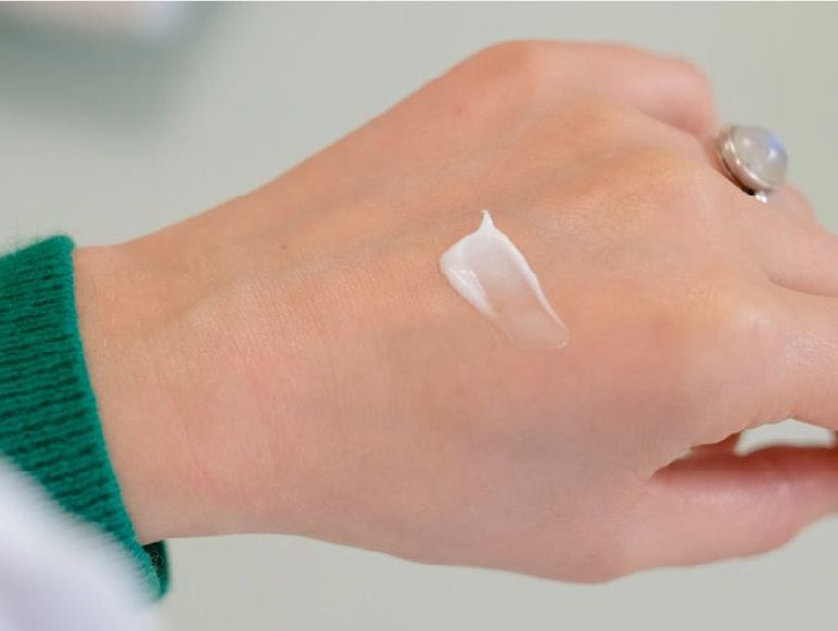 La main d'une fille qui applique de la crème hydratante