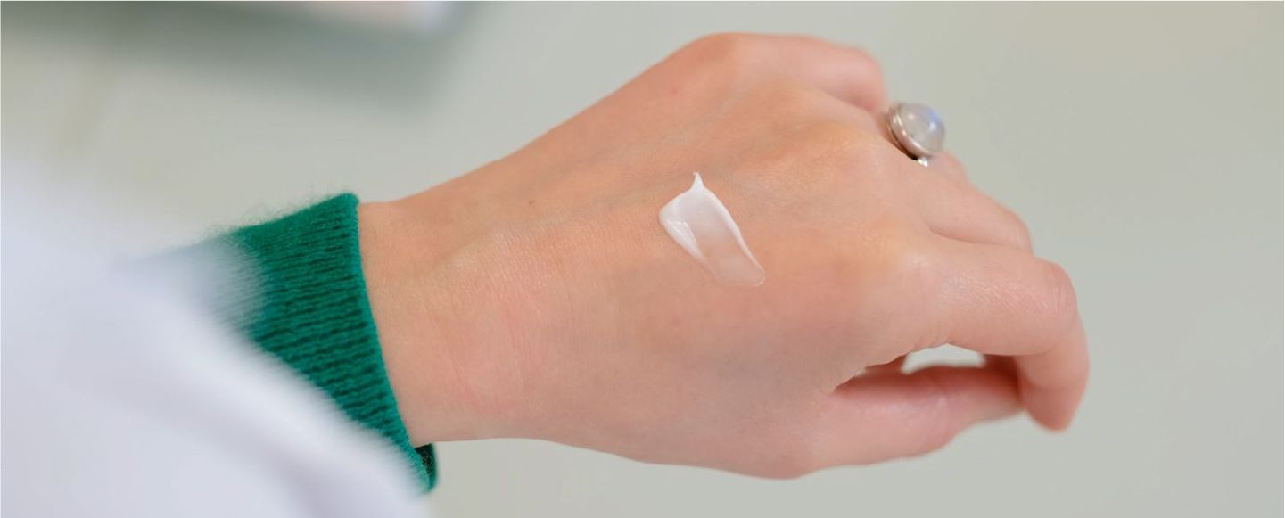 La main d'une fille qui applique de la crème hydratante