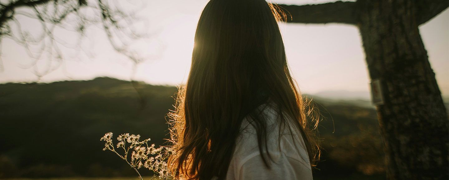 Jeune fille dans un jardin qui regarde le coucher du soleil