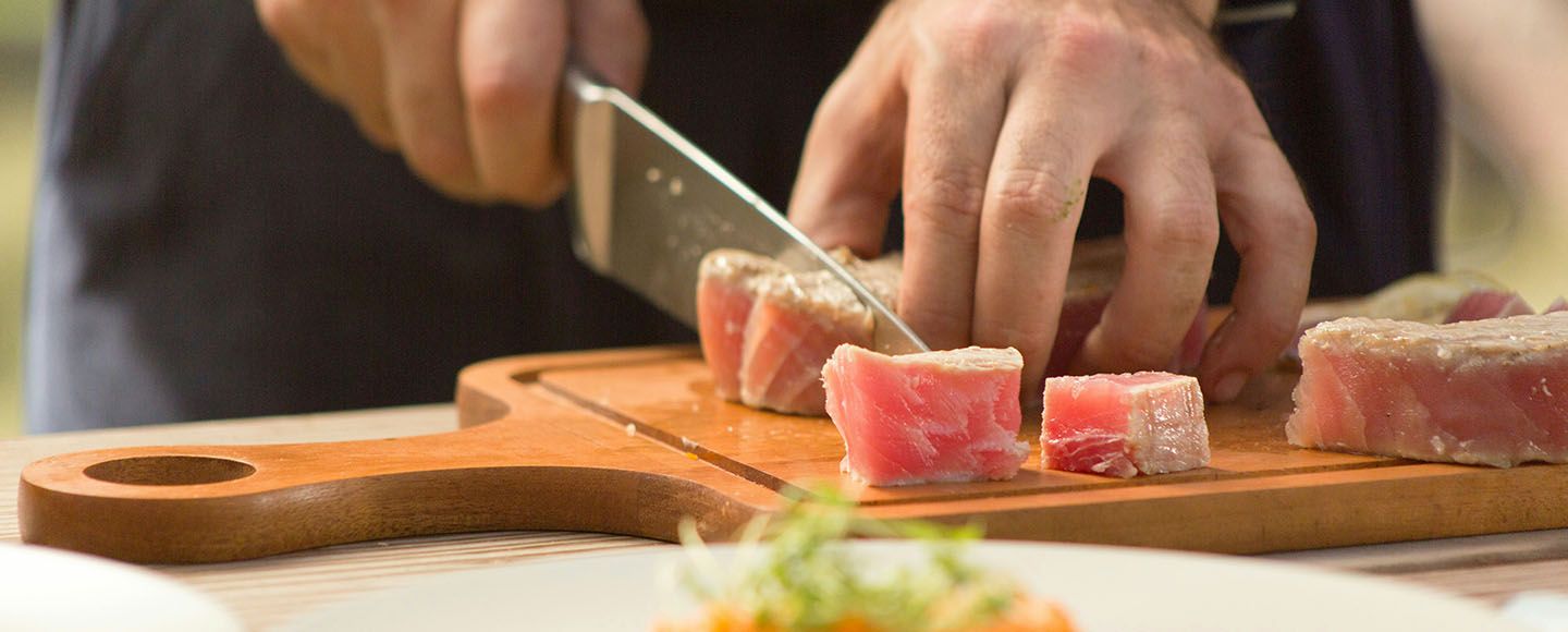 Un homme qui coupe du poisson sur une planche en bois