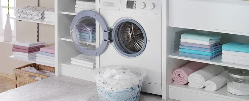Une buanderie avec une machine à laver et du linge dans une pannière