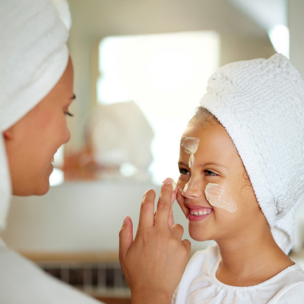 Une maman applique de la crème sur le visage de sa fille