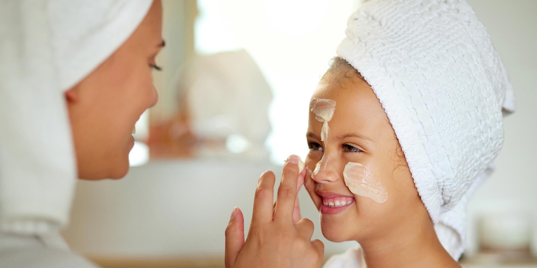 Une femme applique de la crème sur le visage de sa fille
