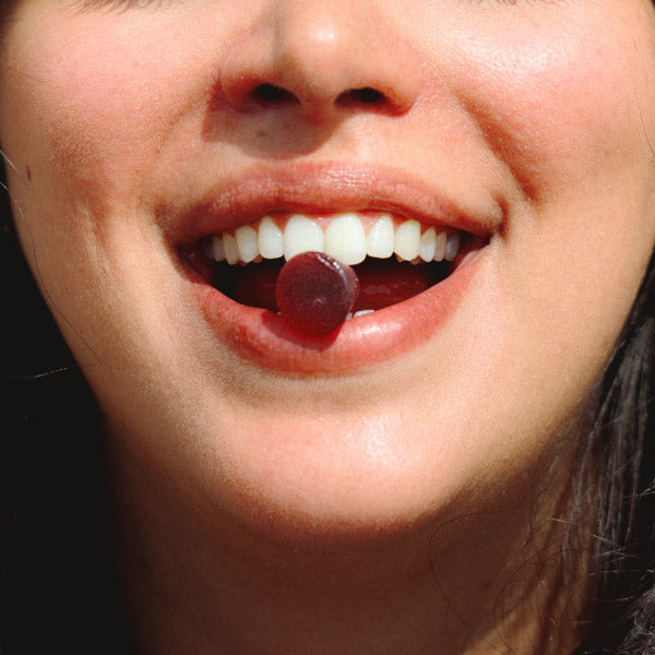 Une bouche avec une gummies immunité coincé entre les dents