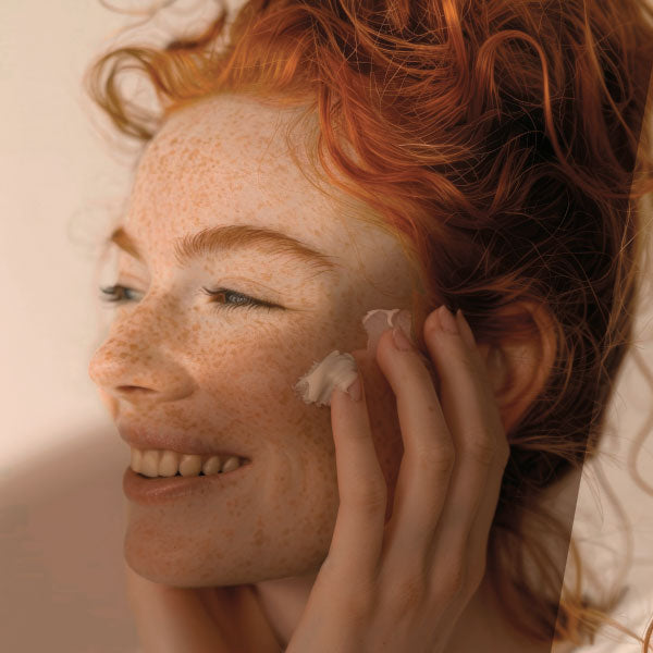 Une femme s'applique de la crème sur le visage 