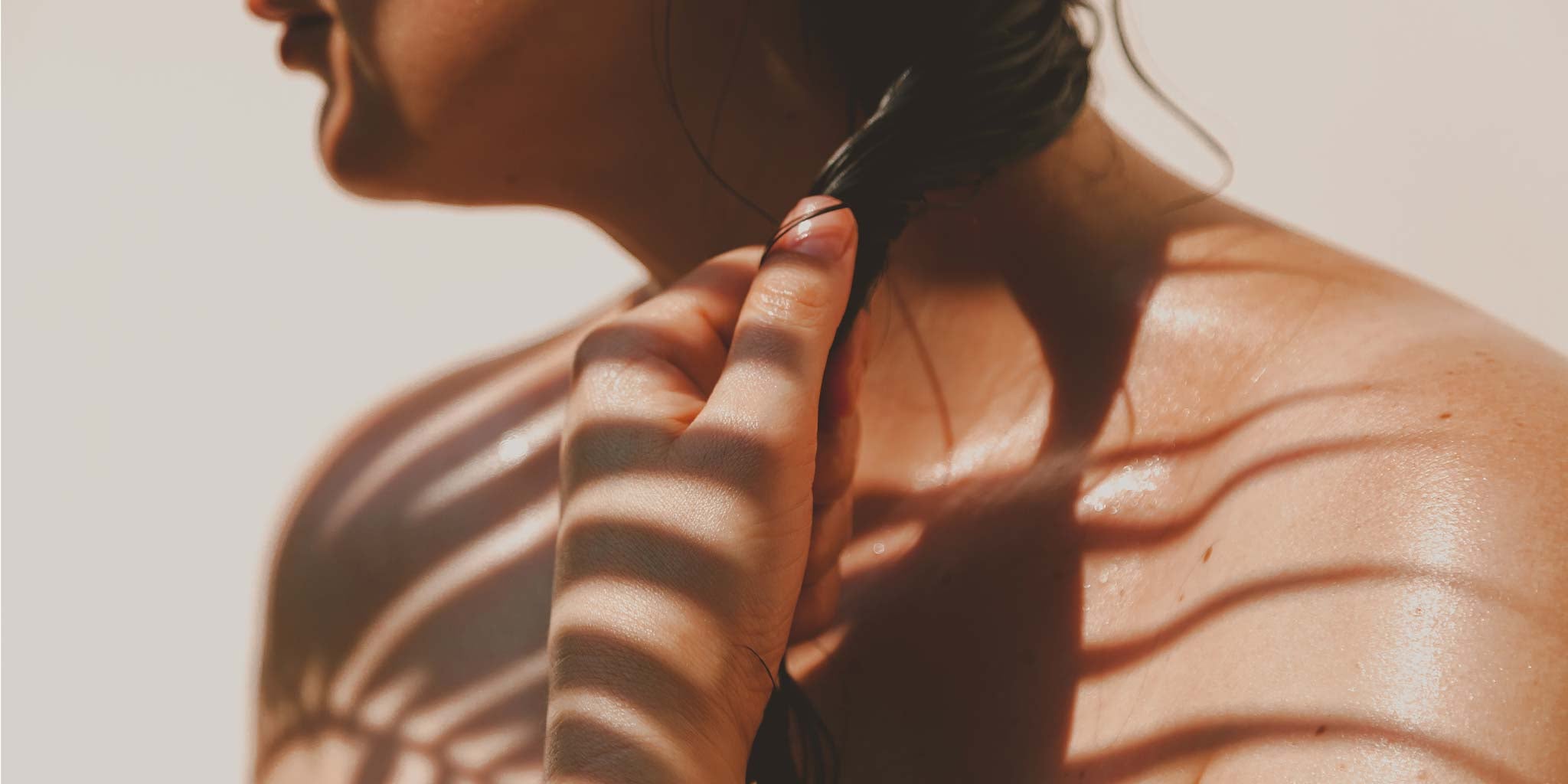 Une femme a les épaules dénudées et se touche les cheveux